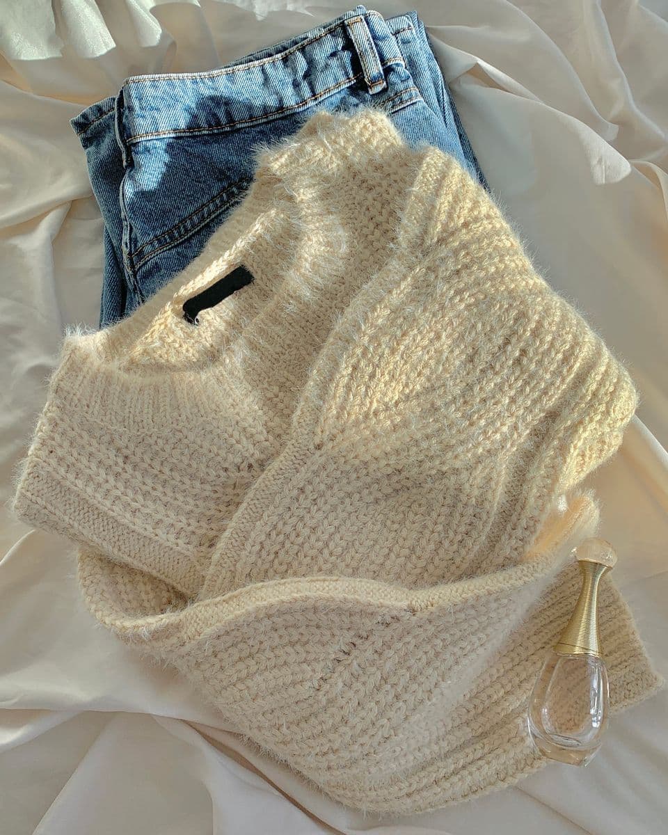 A warm wool sweater paired with jeans, laid out together as a complete outfit