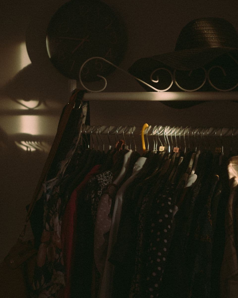 A softly lit clothing rack of garments tucked away, waiting to be worn again